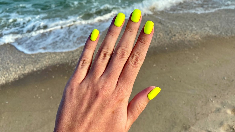 Manicure giallo neon in riva all'oceano