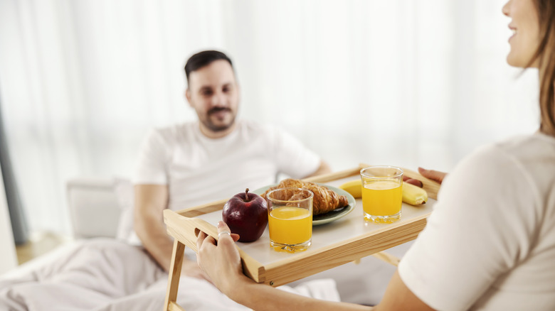 Una donna porta la colazione a letto al suo compagno