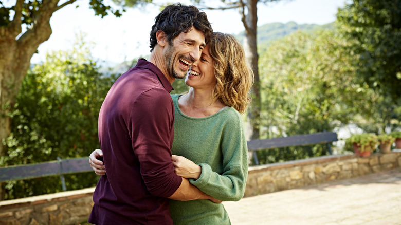 Uomo e donna che si abbracciano e ridono all'aperto