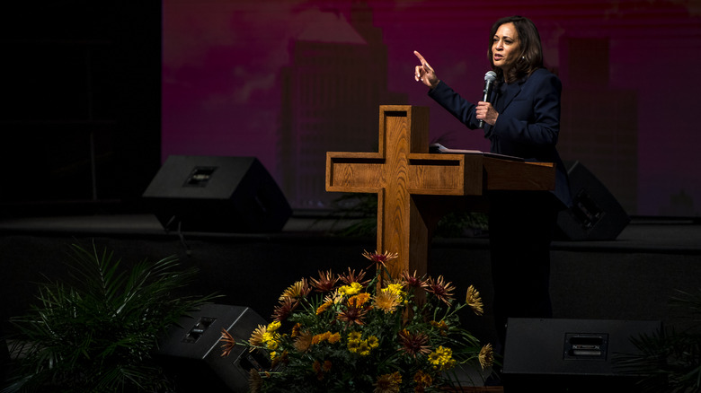 Kamala Harris parla in una chiesa dietro un podio a forma di croce