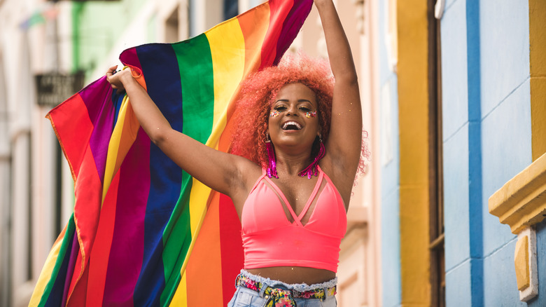 Donna che tiene in mano la bandiera del Pride con un top rosa