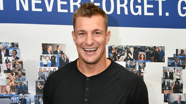 Rob Gronkowski sorride indossando una maglietta nera abbottonata