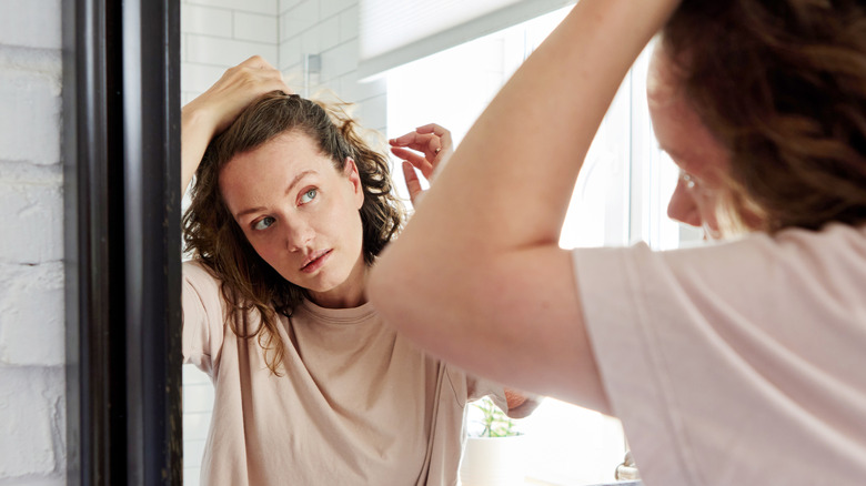 Donna che esamina i capelli allo specchio