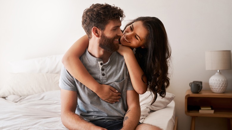 Coppia sorridente che si abbraccia in camera da letto