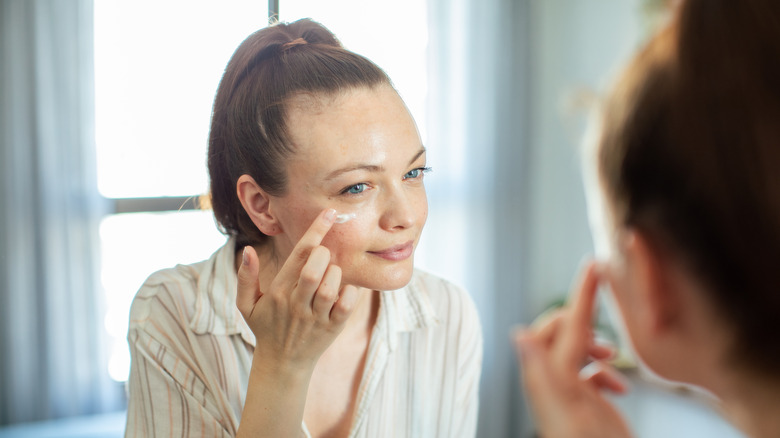 Donna che applica la crema per gli occhi