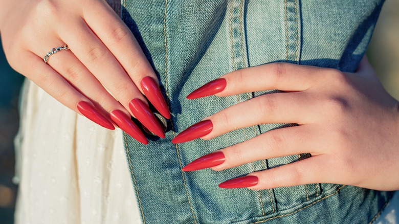 Mani di donna con unghie rosse a stiletto