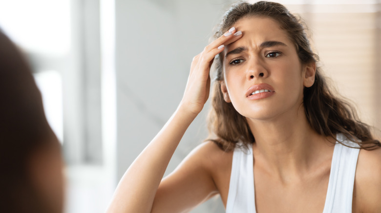 Giovane donna che esamina le rughe sulla fronte