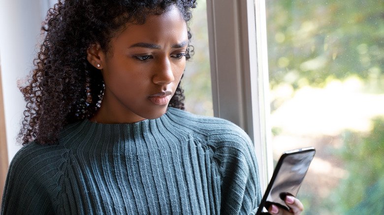 Donna che guarda gelosamente il telefono