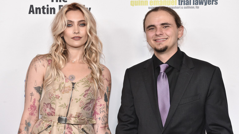 Paris Jackson indossa un abito floreale color cuoio con Prince Jackson che indossa una giacca nera, una camicia nera e una cravatta viola