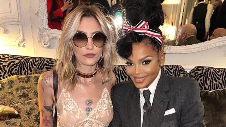 Paris Jackson indossa una canottiera in pizzo e occhiali da sole con Janet Jackson che indossa una giacca nera, una camicia bianca e una cravatta nera