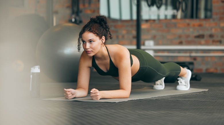 Donna che tiene la tavola in palestra