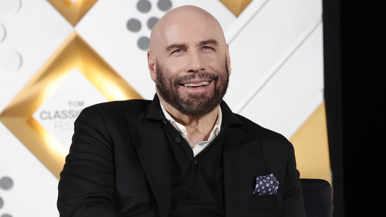 John Travolta seduto e sorridente