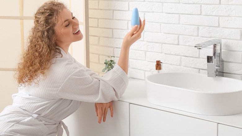 Donna in bagno che guarda il deodorante