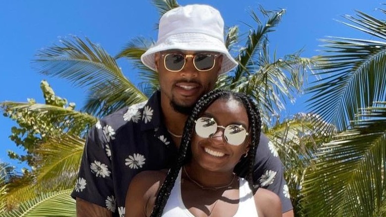 Jonathan Owens con una camicia floreale e un cappello da pescatore bianco e Simone Biles con una canotta bianca