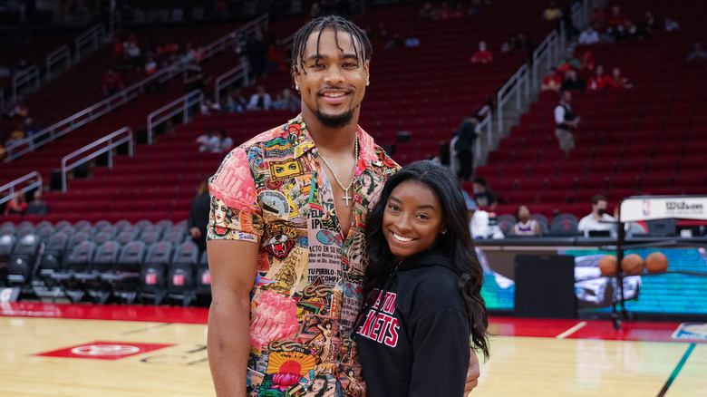 Jonathan Owens indossa una camicia con bottoni e Simone Biles indossa una felpa con cappuccio nera