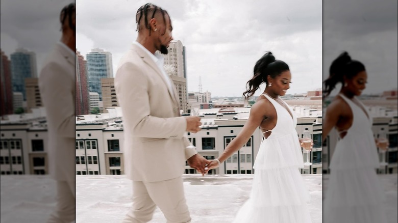 Jonathan Owens in uno smoking beige e bianco e Simone Biles in un abito da sposa bianco