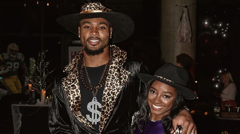 Jonathan Owens con un cappello e una giacca leopardati con Simone Biles che indossa un cappello nero e una camicia viola