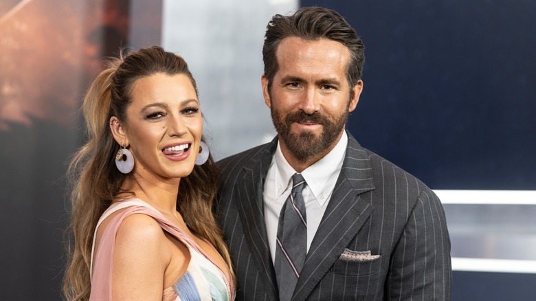 Blake Lively indossa un abito multicolore con Ryan Reynolds che indossa un completo gessato grigio e cravatta