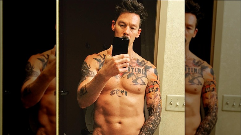 David Bromstad senza maglietta mentre guarda il telefono