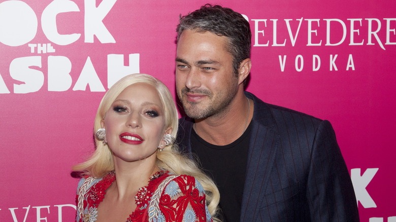 Lady Gaga indossa un abito di perline multicolori con Taylor Kinney che indossa una giacca gessata blu sul tappeto rosso