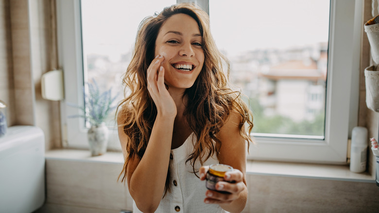 Donna sorridente che applica la crema ghee