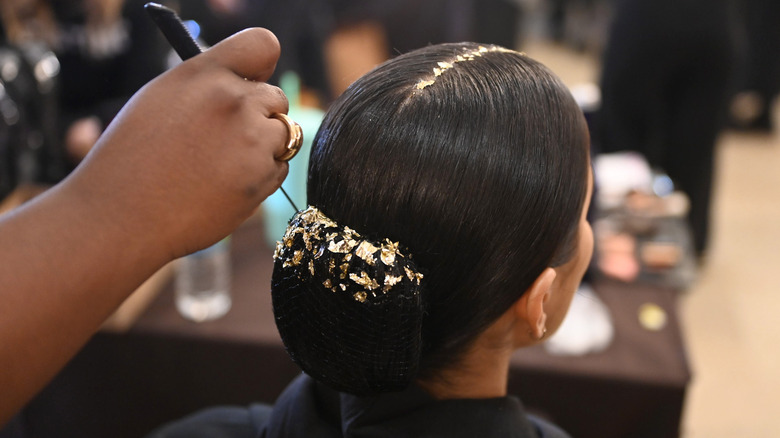 Modella con capelli ricoperti di foglie d'oro