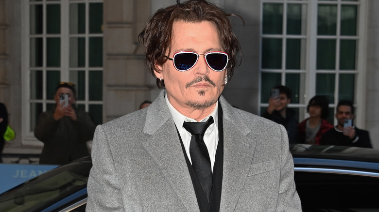 Johnny Depp indossa occhiali da sole in un soprabito grigio