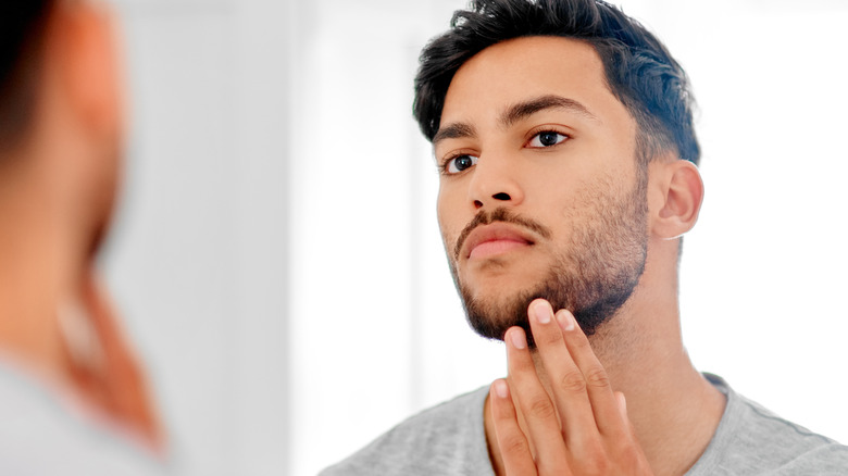 Uomo che esamina la barba allo specchio