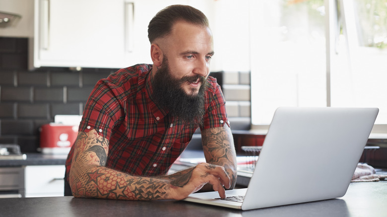 Uomo barbuto che usa il computer portatile