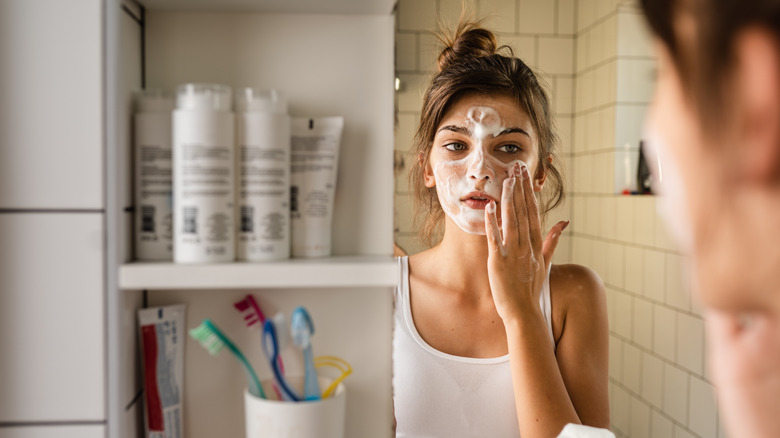 Donna che si lava il viso con il detergente