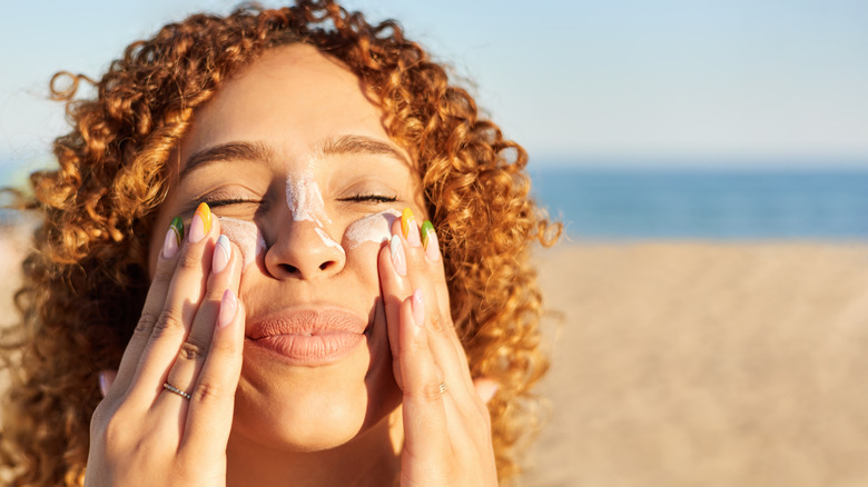 Donna sorridente che applica la crema solare sul viso