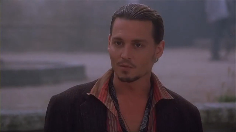 Johnny Depp indossa una giacca marrone e una camicia con colletto a righe rosse e marroni