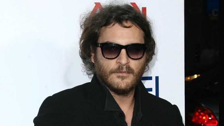 Joaquin Phoenix indossa occhiali da sole neri e una giacca nera