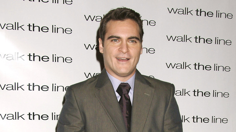 Joaquin Phoenix indossa un abito grigio e una cravatta viola sul tappeto rosso