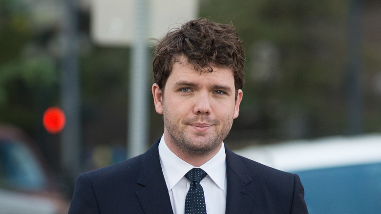 Austin Swift cammina per strada in giacca e cravatta