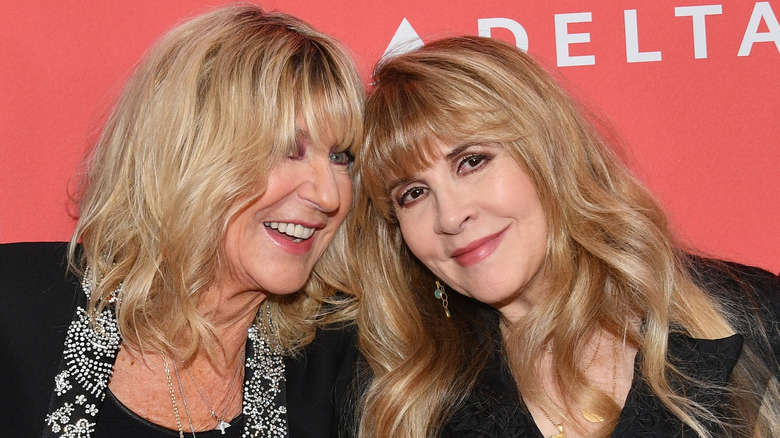 Christine McVie indossa una giacca nera con finiture decorate in argento e Stevie Nicks indossa una giacca nera e orecchini dorati e verdi