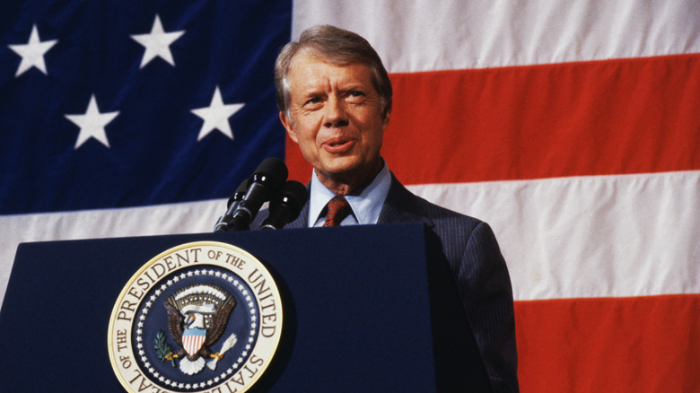 Jimmy Carter parla ai cittadini di Elk City con la bandiera americana dietro di lui