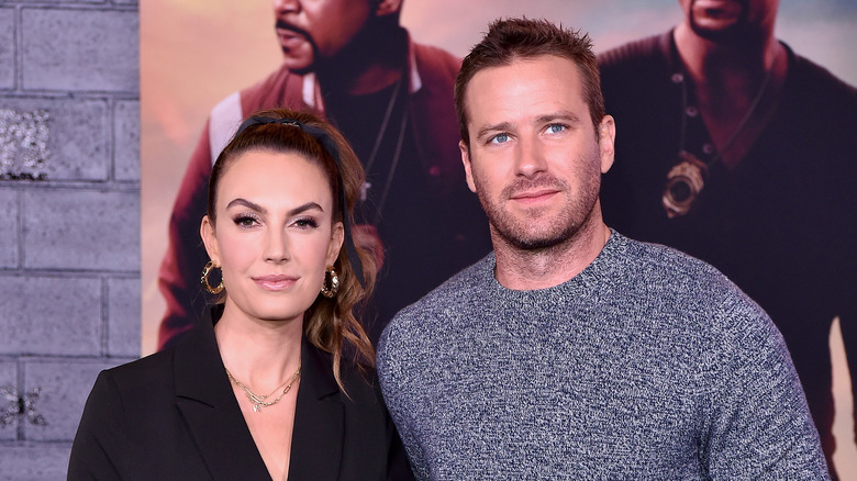 Elizabeth Chambers indossa una camicetta nera e Armie Hammer indossa un maglione grigio-blu