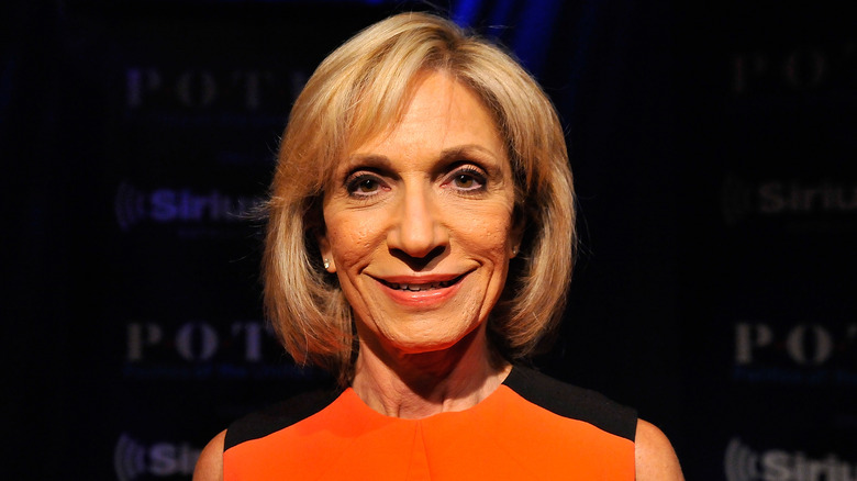 Andrea Mitchell sorridente in un abito arancione e nero