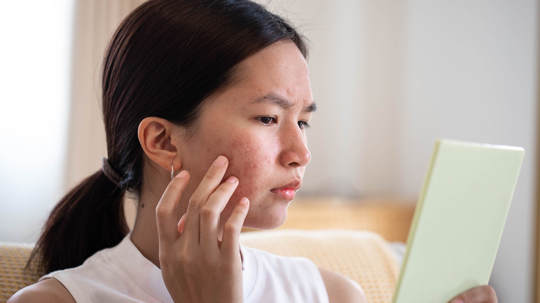 Una donna che esamina il suo viso