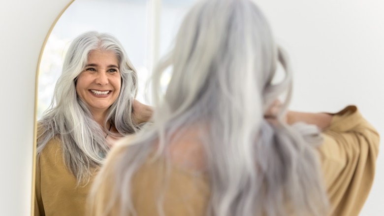 Donna dai capelli bianchi che si guarda allo specchio