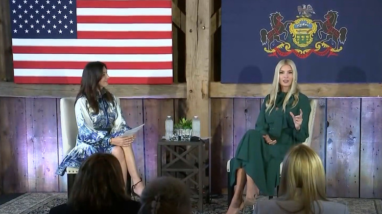 Ivanka Trump seduta e parla sul palco con un abito verde