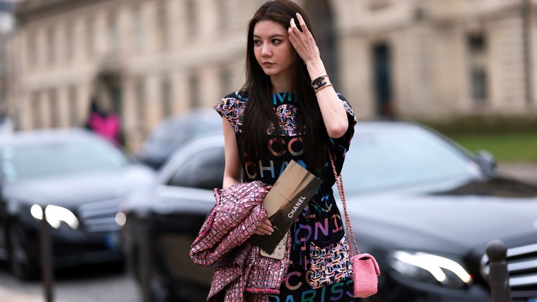 Donna con abito, borsa e braccialetto con logo Chanel