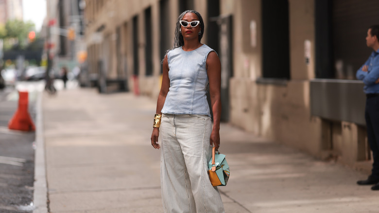 Una donna che indossa una camicia di jeans blu e pantaloni a righe.