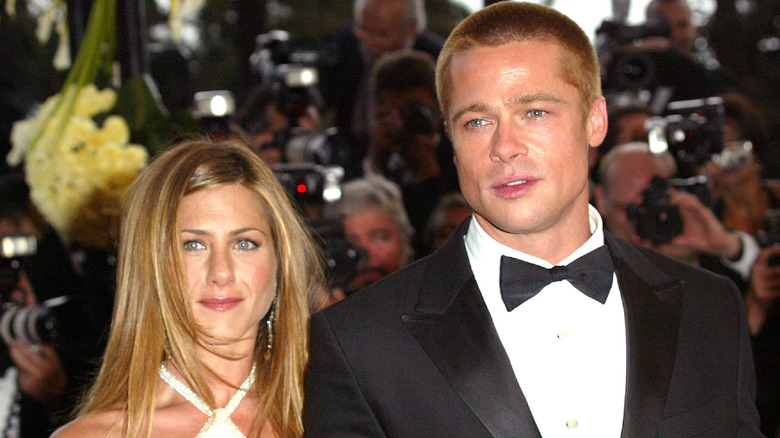 Jennifer Aniston indossa un abito incrociato e Brad Pitt indossa uno smoking nero e un papillon