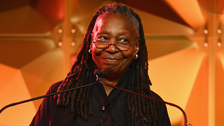 Whoopi Goldberg sorride mentre guarda un podio