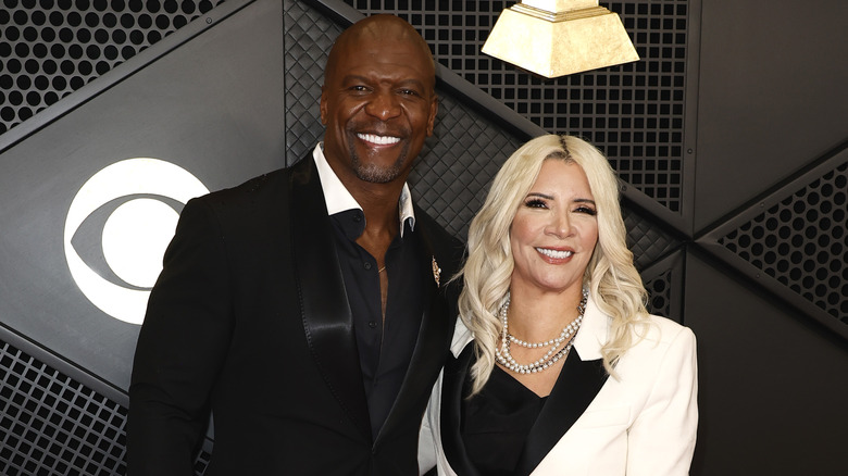 Terry Crews e Rebecca King-Crews sorridono con i denti e indossano abiti in bianco e nero