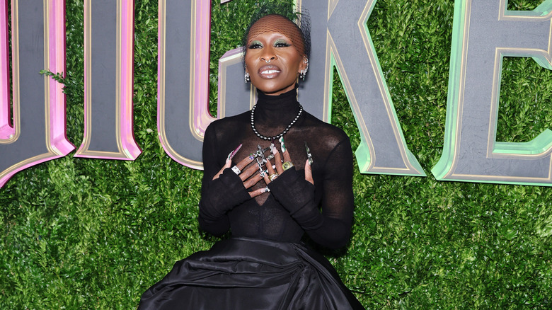 Cynthia Erivo indossa un abito nero e mette le mani sul cuore in a 