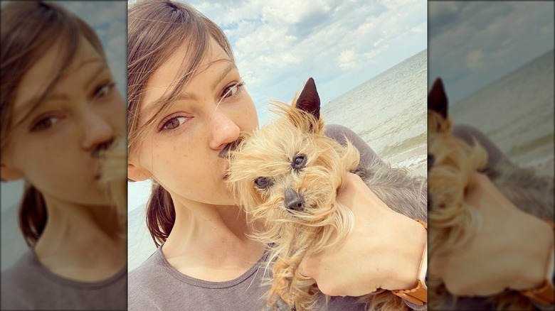 Aimeé Teegarden bacia il suo cane Gizmo sulla fronte in spiaggia.