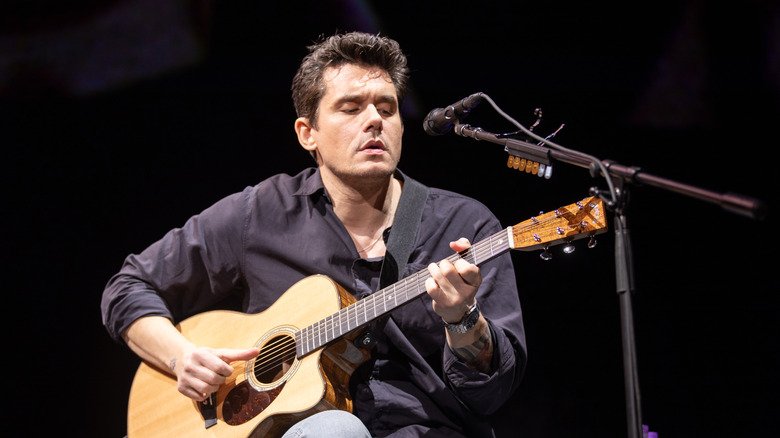 John Mayer sul palco suona la chitarra davanti a un microfono